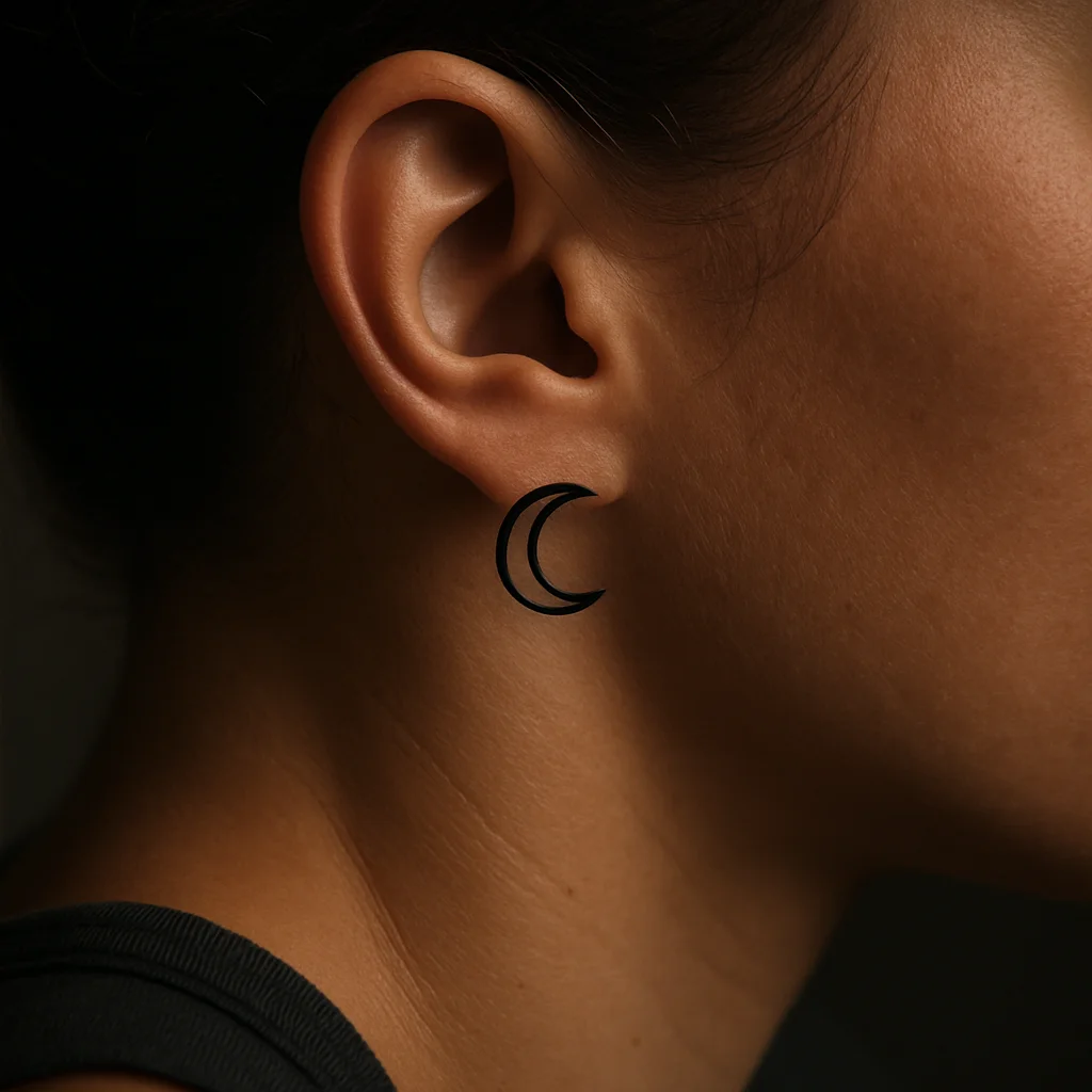 Minimalist open crescent moon outline tattooed behind the ear